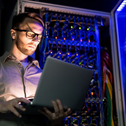 Limited, PAYE and umbrella explained - IT engineer on a laptop in a server room in the dark