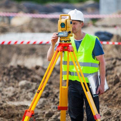 A surveyor using a theodolite on a construction site.