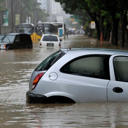 Flooded city street with submerged cars after heavy rainfall.